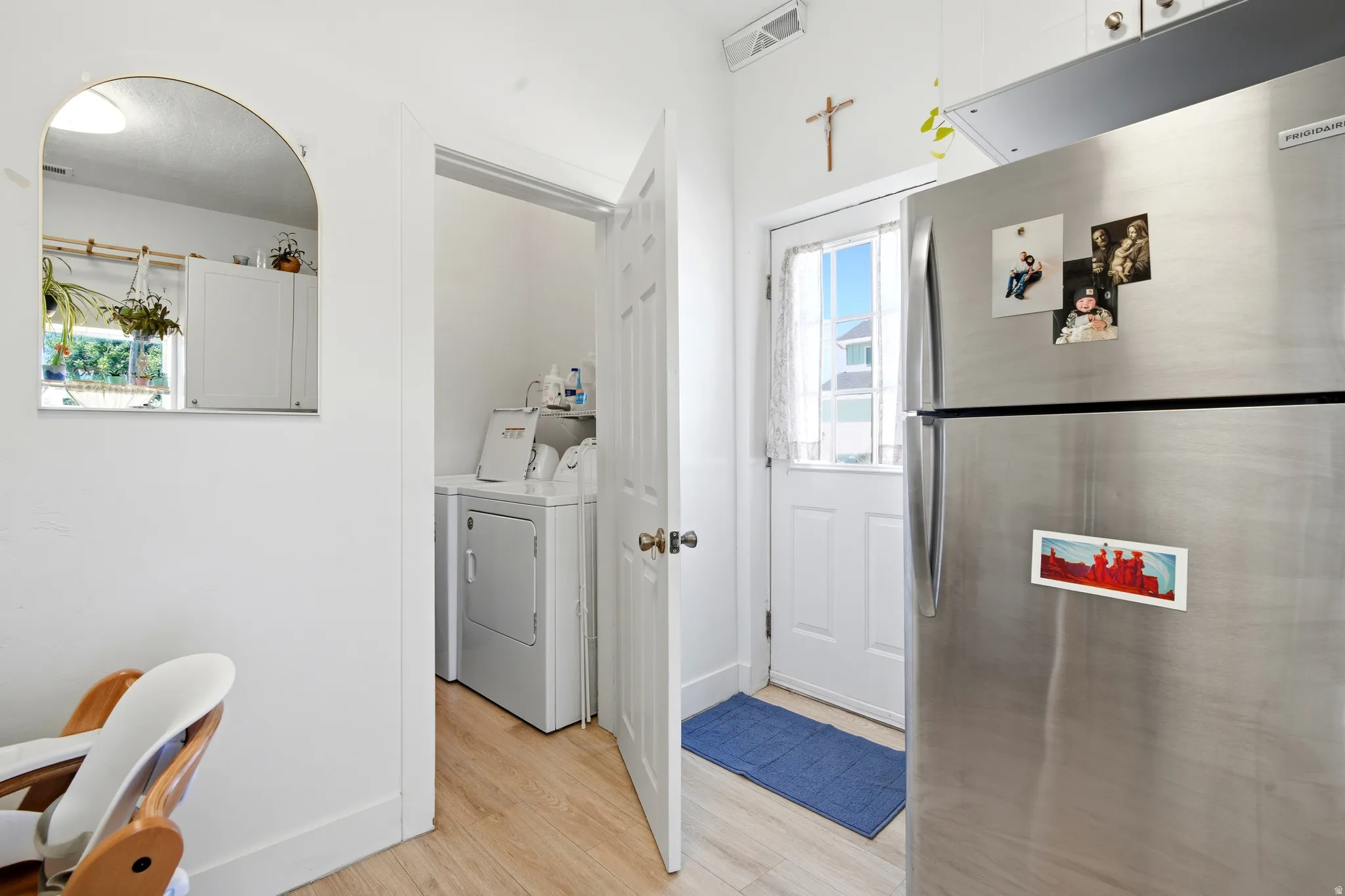 Laundry area featuring a stacked washer and dryer, wood-finish flooring, and a white paneled door with window