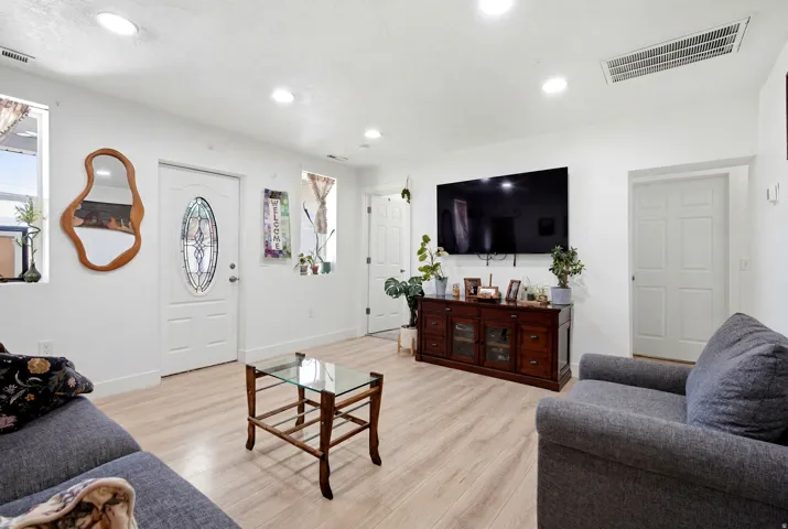 Living area featuring wood-finish flooring, recessed lighting, and white paneled doors