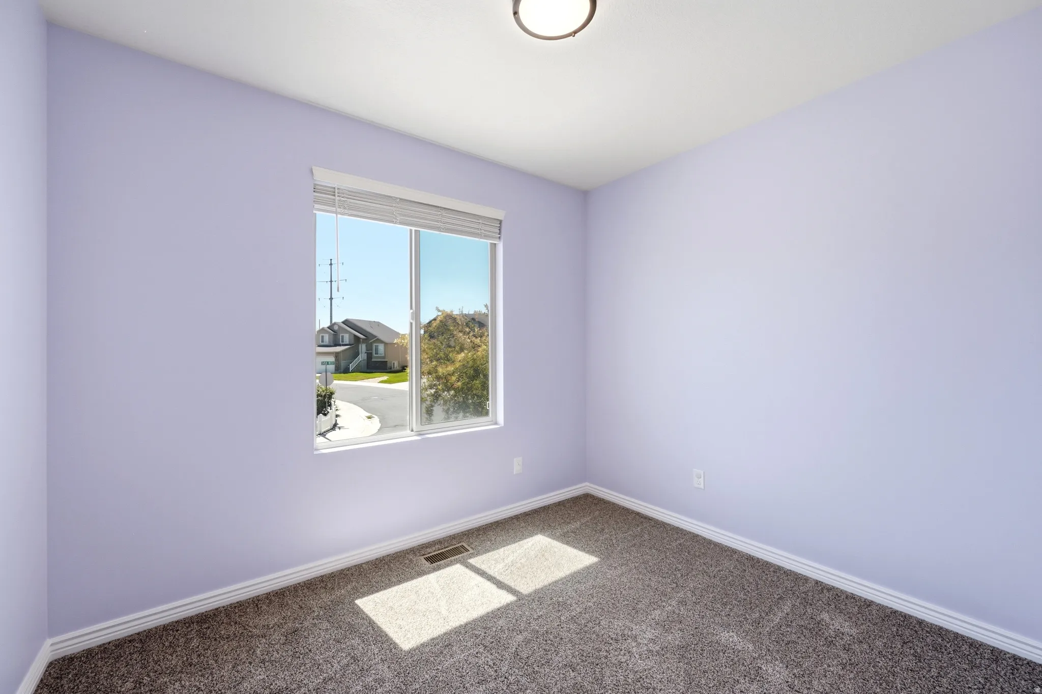 Interior room with light lavender walls, gray textured carpeting, and white baseboards