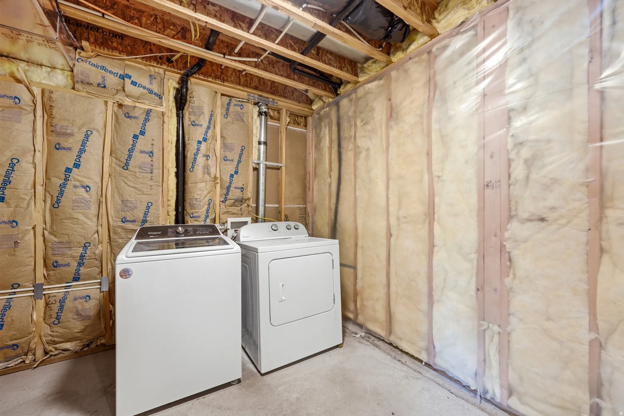 Unfinished basement area featuring exposed wood framing, ceiling joists, and visible insulation