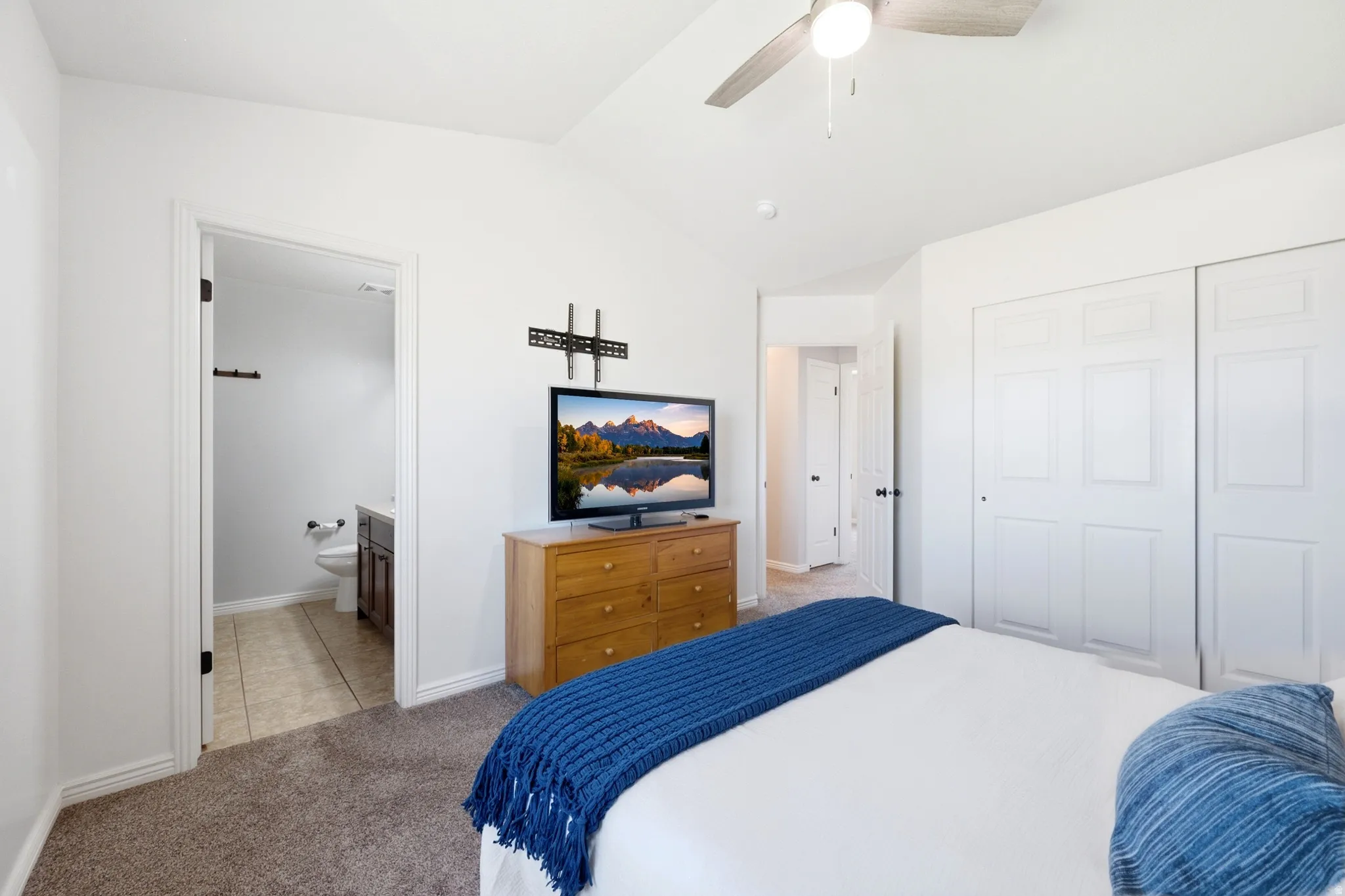 Carpeted interior space featuring a vaulted ceiling with a ceiling fan