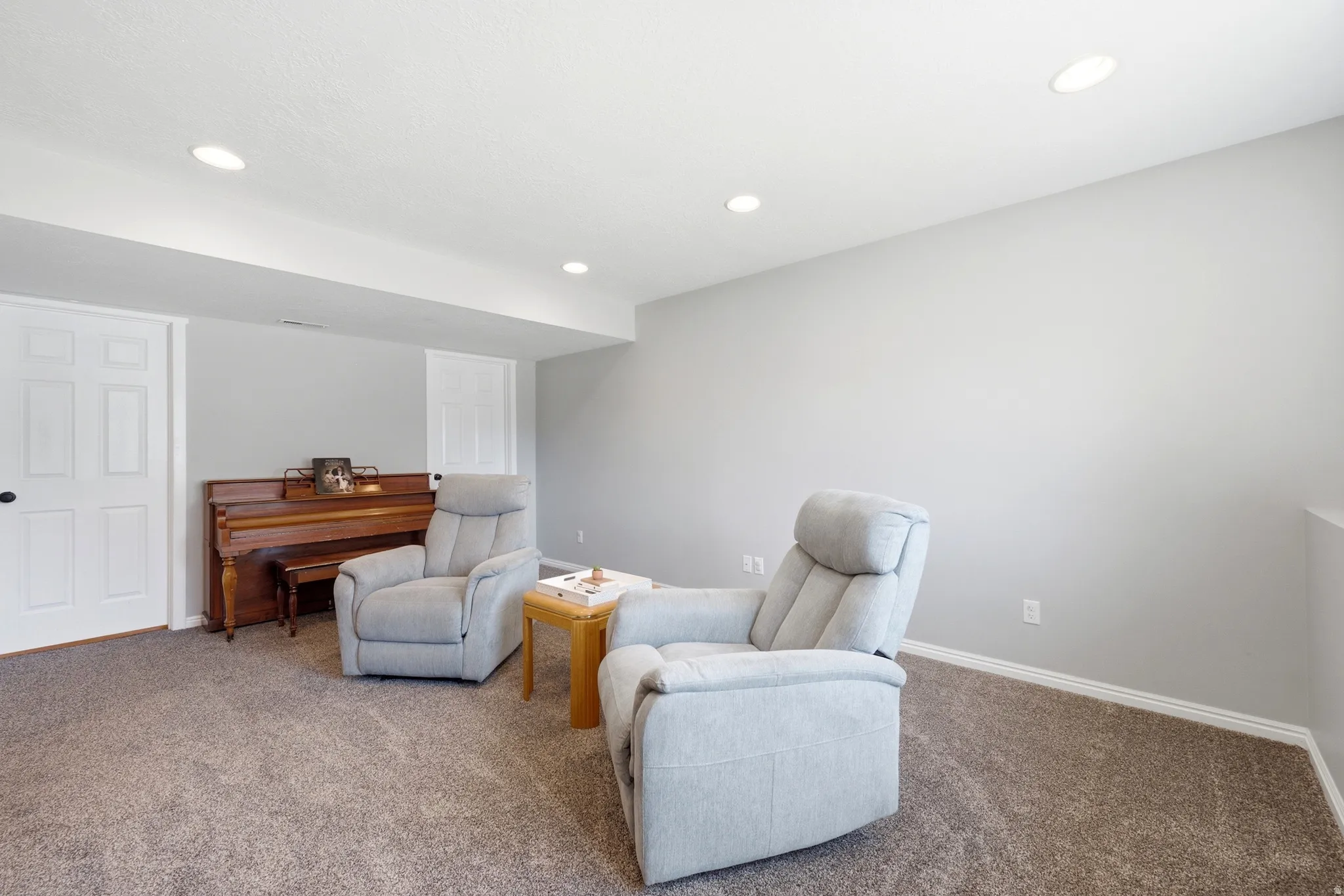 Spacious room featuring neutral gray wall paint, recessed lighting, white trim, and plush carpet flooring