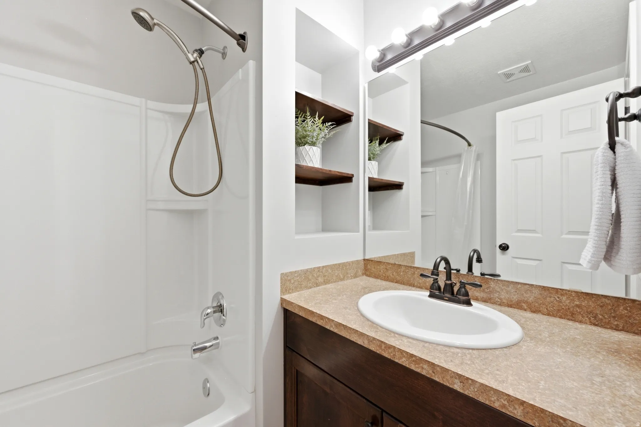 Full bathroom featuring a white tub and shower combination with a handheld showerhead