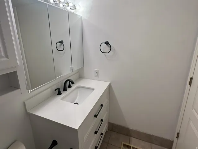 White vanity with a rectangular undermount sink, quartz countertop, and matte black faucet