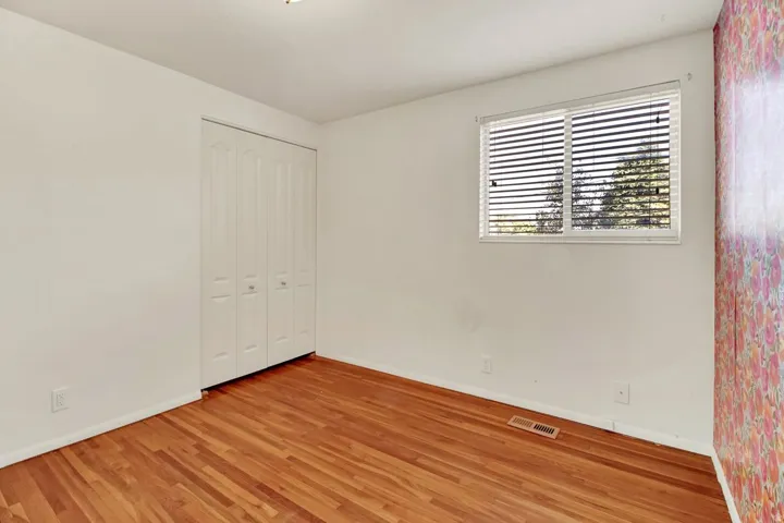 Main level Bedroom  featuring wood-finish flooring, white walls, and a window with horizontal blinds
