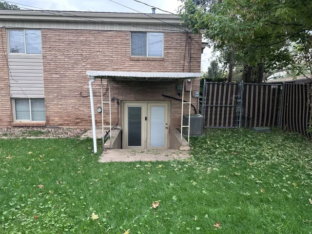 Brick exterior with a covered basement entry and a fenced yard