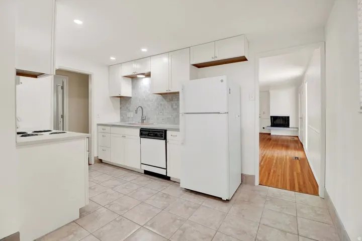 Kitchen featuring white cabinetry, tile flooring, stone-look backsplash, stainless steel sink with a gooseneck faucet, and recessed lighting