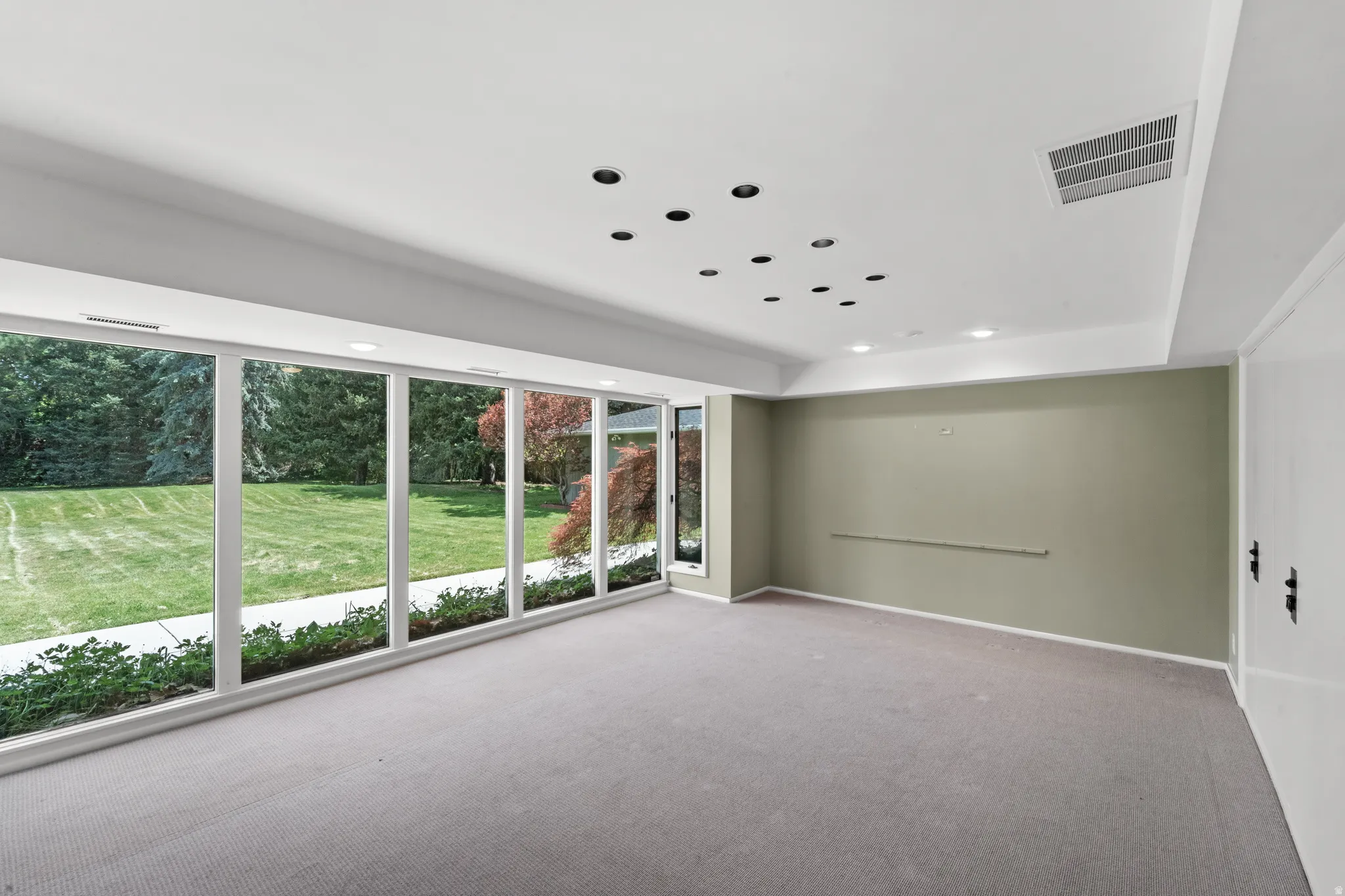 Room featuring a wall of floor-to-ceiling windows, recessed lighting, carpeted flooring, and a neutral wall color
