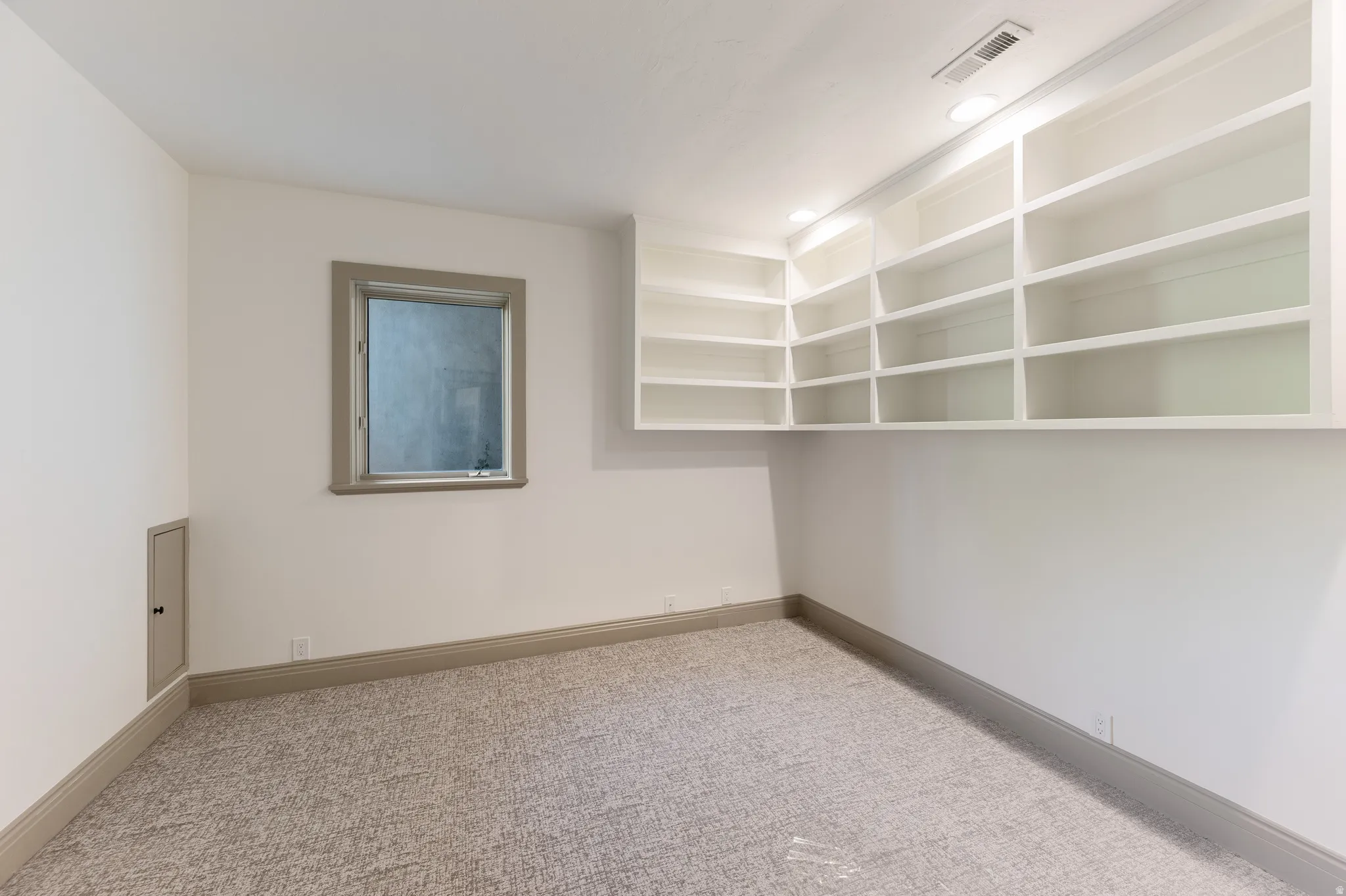 Room with extensive built-in shelving, recessed lighting, and neutral-toned carpet