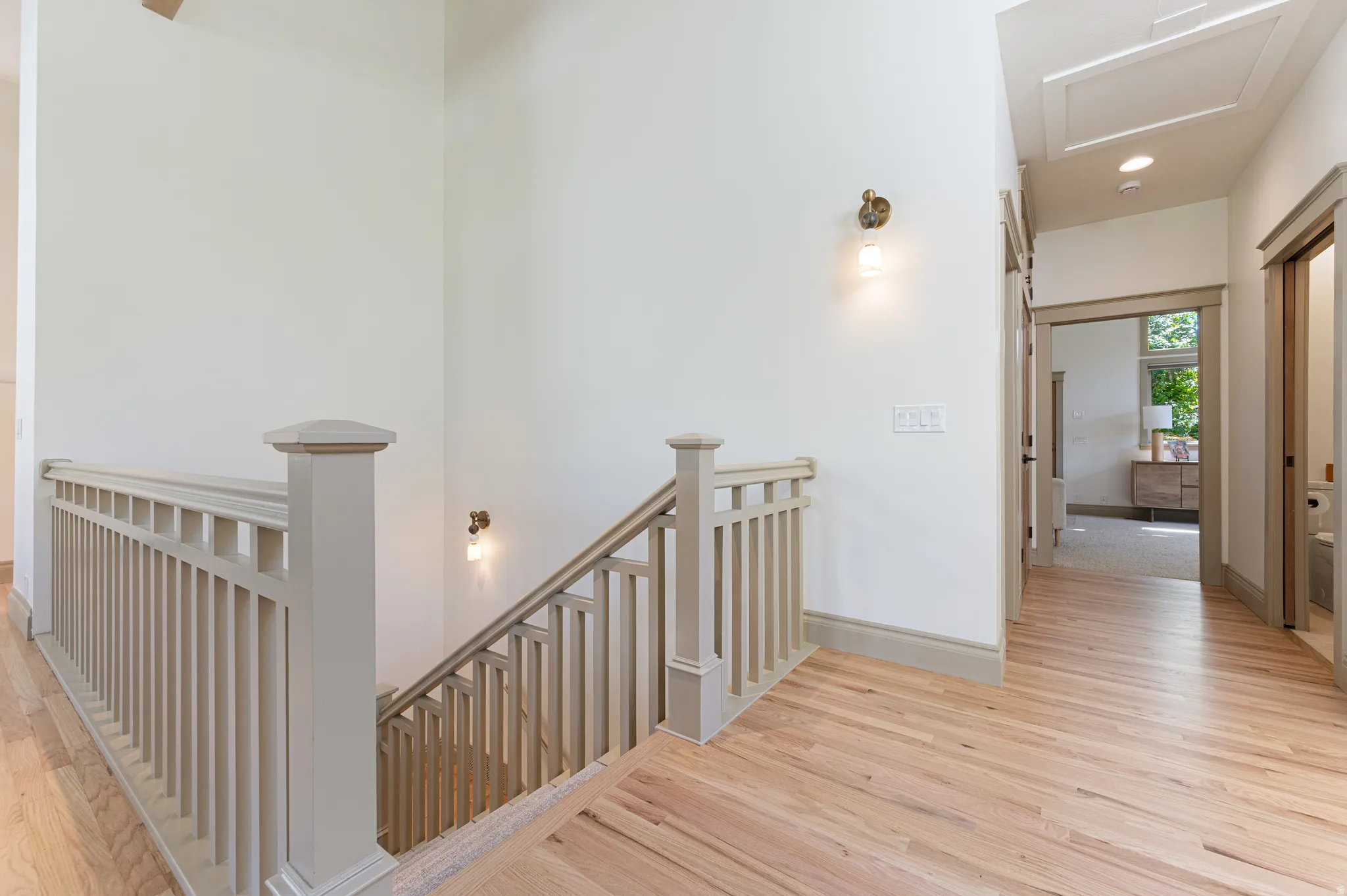 Stairwell featuring light-toned wood-finish flooring, white walls, and a painted balustrade with square pickets