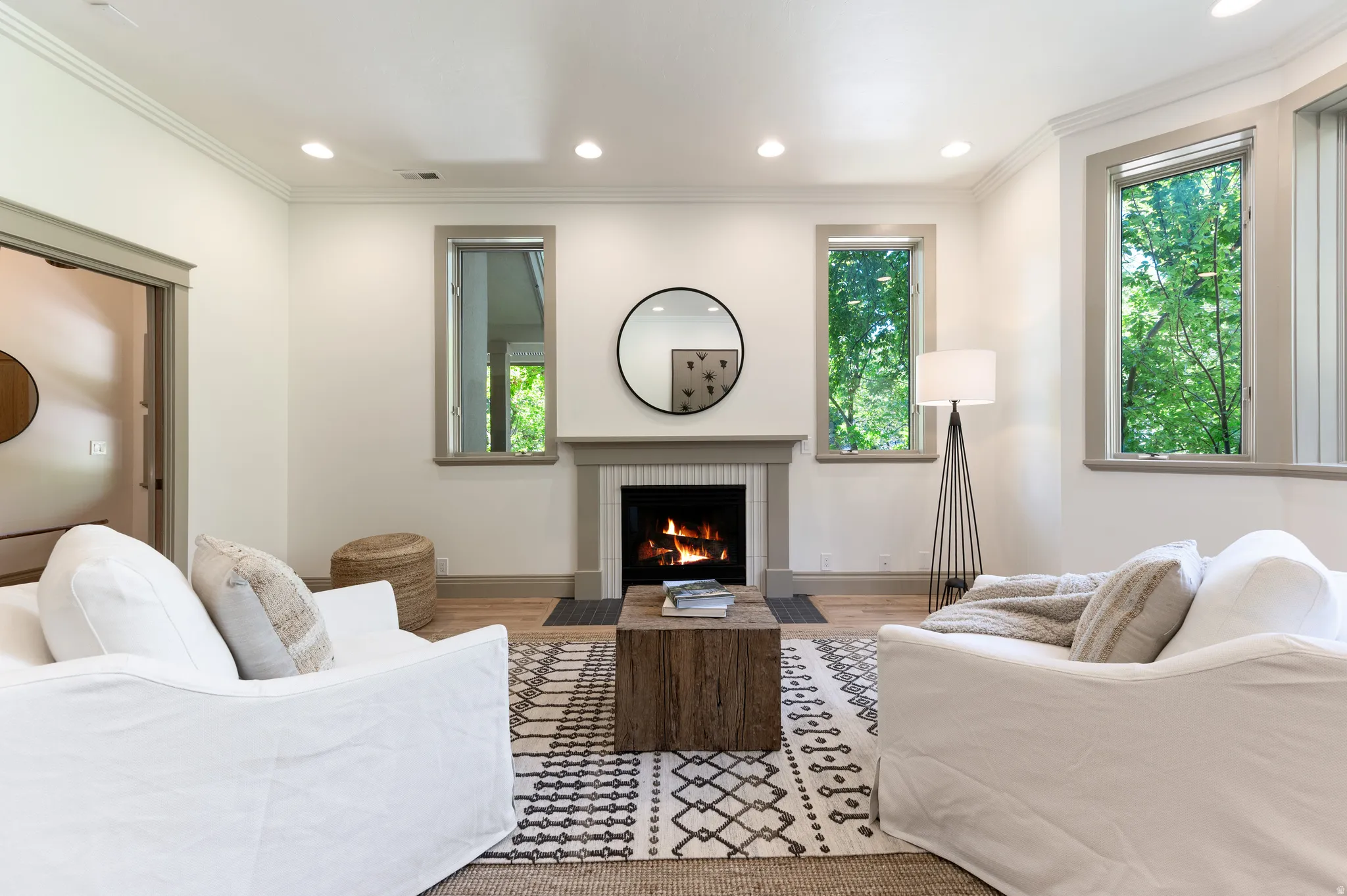 Living area featuring a fireplace with a light-toned mantel, recessed lighting, wood-finish flooring, and crown molding