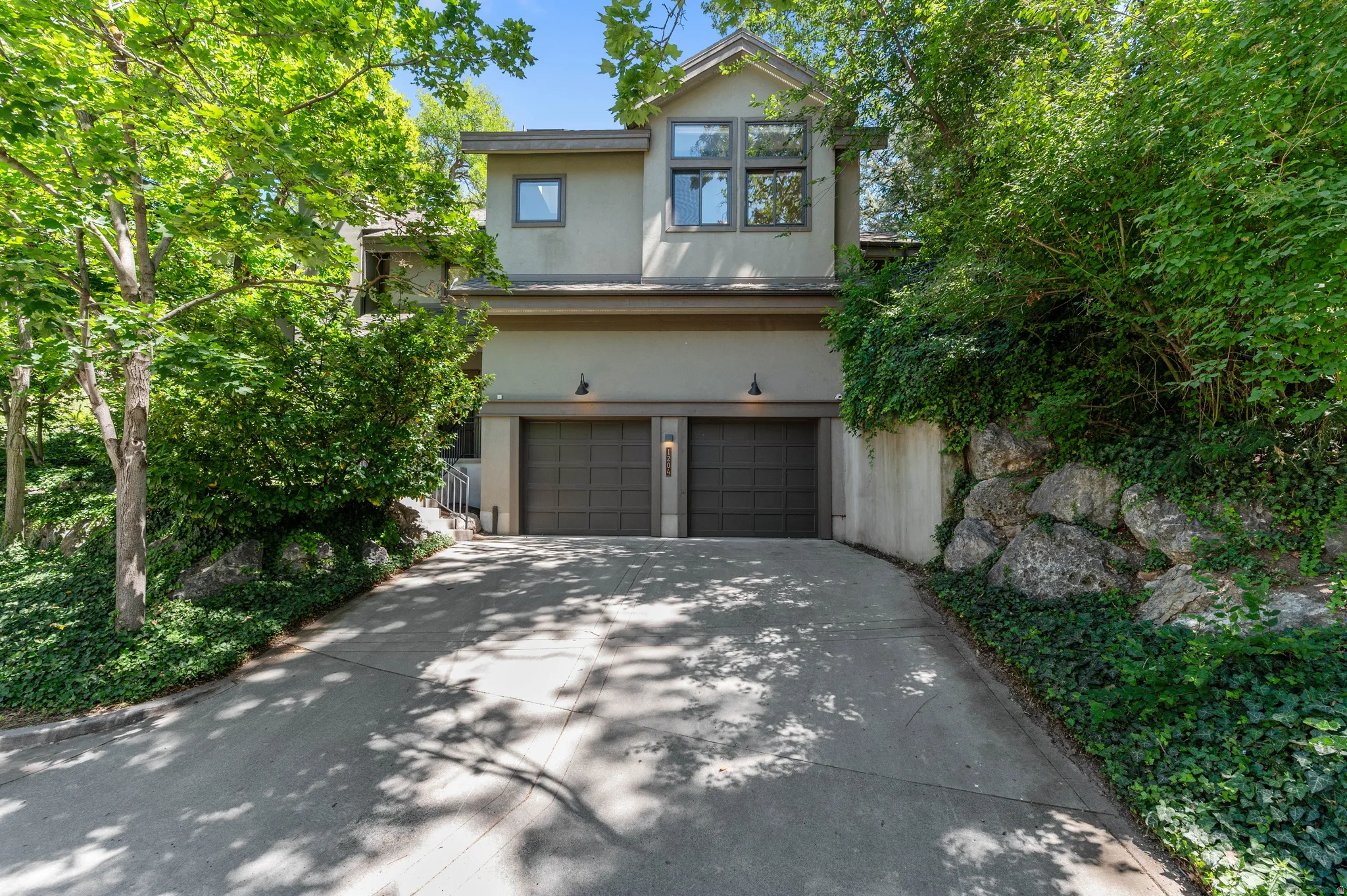 Contemporary exterior featuring a two-car garage with panel doors, upper-level casement windows, and a concrete driveway