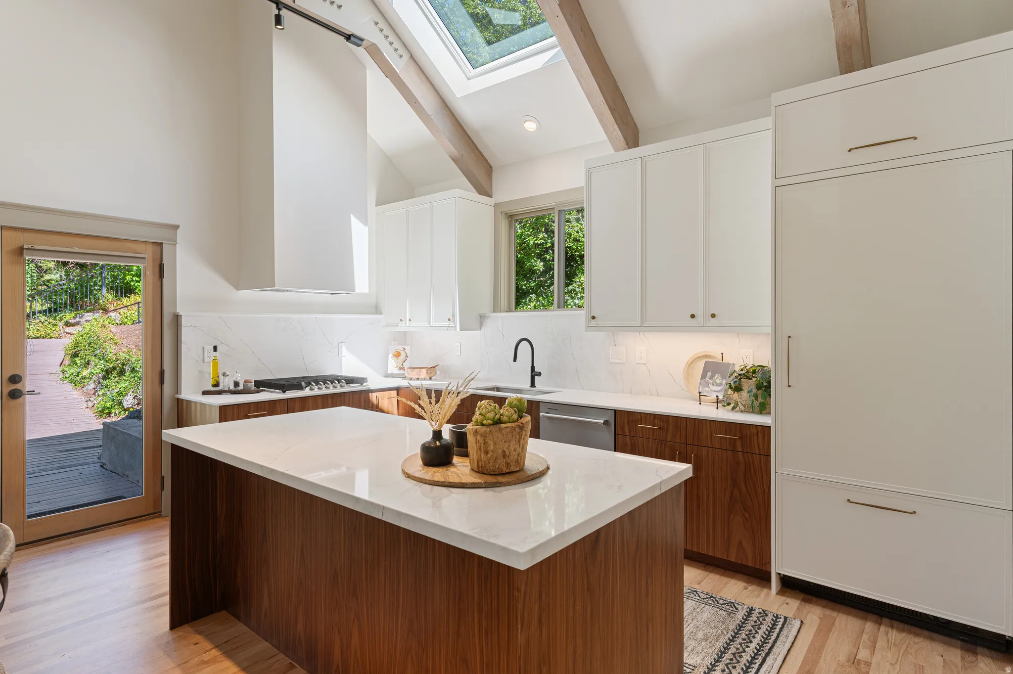 Kitchen featuring a central island with a light-toned countertop, wood-finish base cabinetry, and a skylight