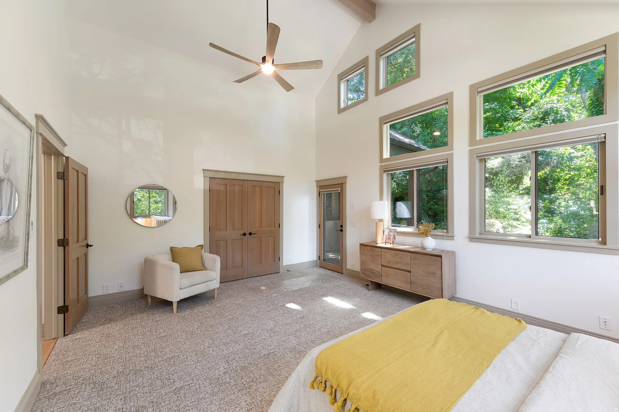 Vaulted ceiling with exposed wood beams, ceiling fan, multiple windows, wood-finish doors, and carpet flooring