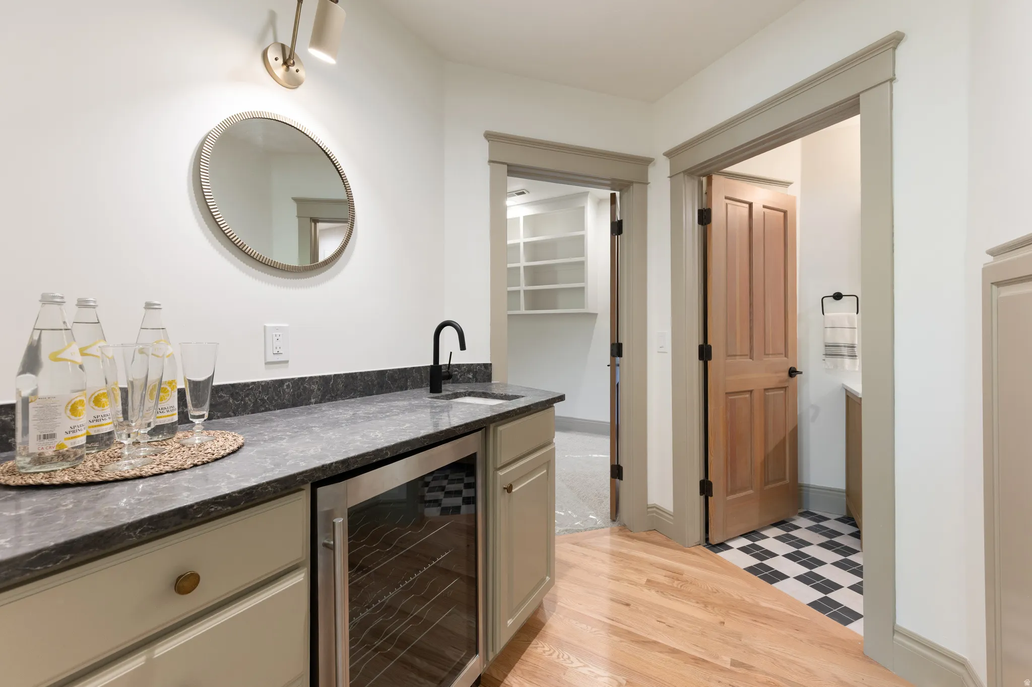 Built-in wet bar featuring a dark countertop, undermount sink with a matte black faucet, and a beverage refrigerator