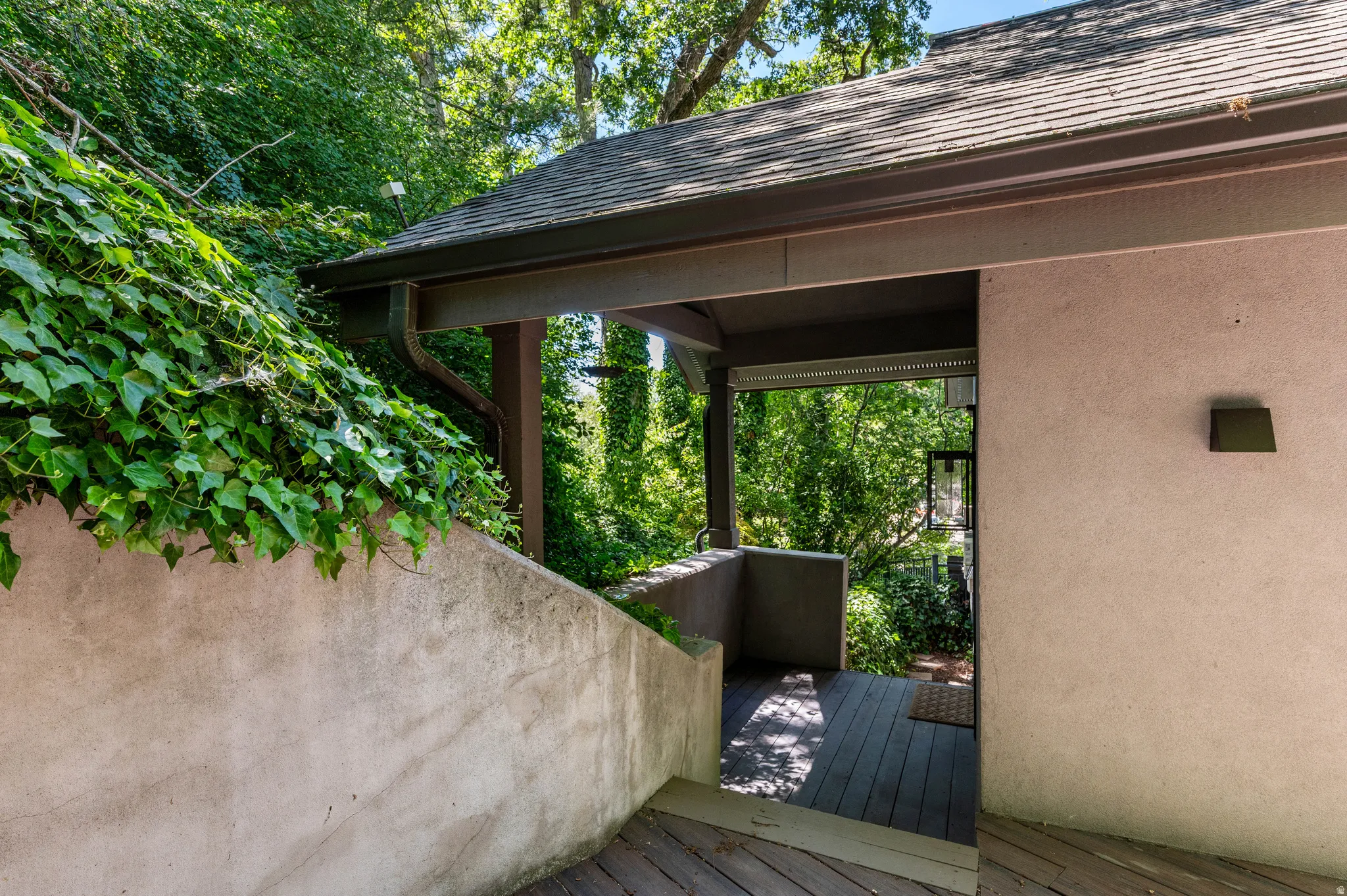 Covered exterior walkway featuring wood-finish decking and stucco walls