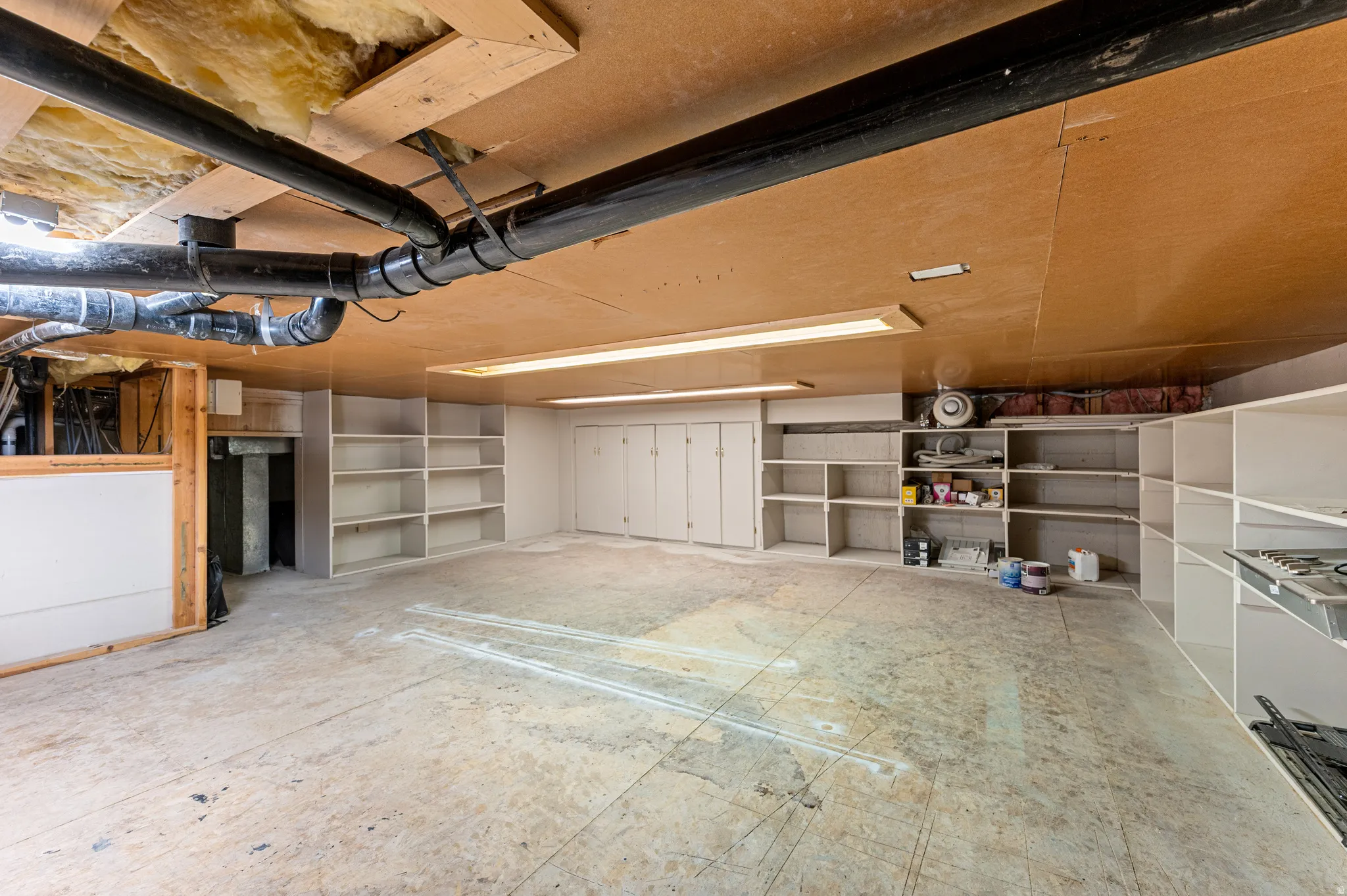 Spacious utility room featuring built-in shelving, ample storage cabinetry, and exposed ceiling joists