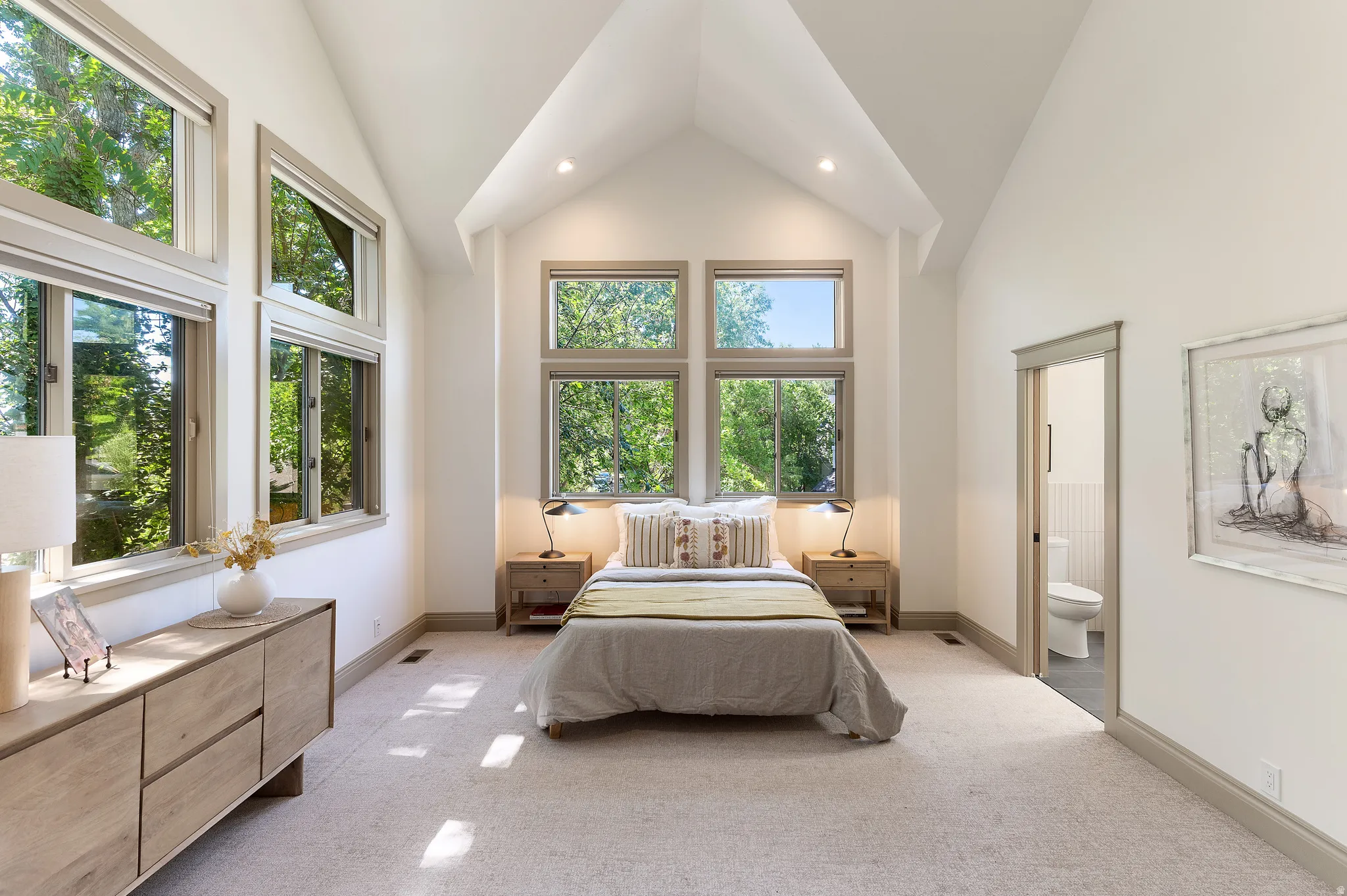 Vaulted ceiling room featuring multiple large windows, recessed lighting, and light-toned carpeting
