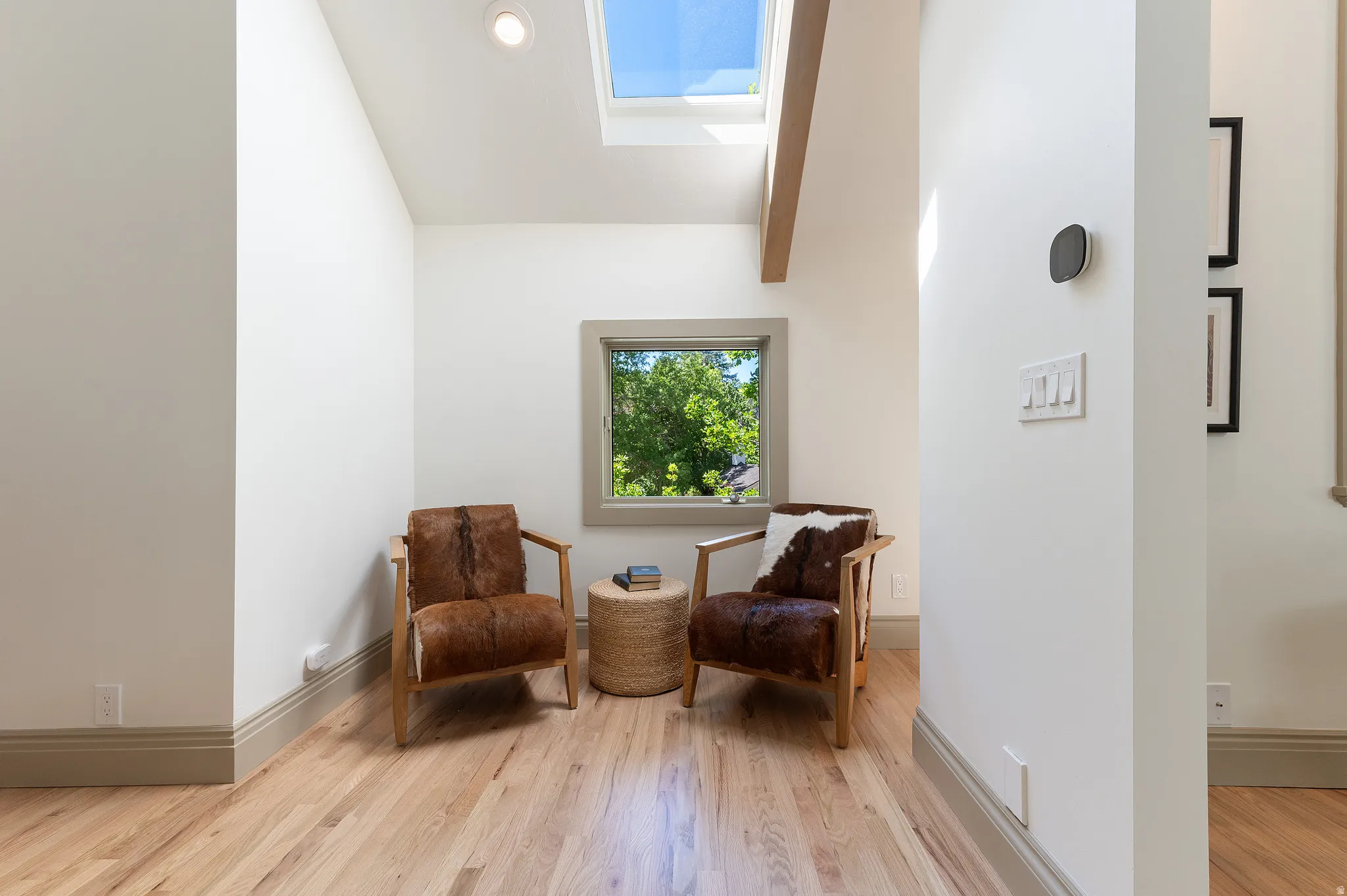 Vaulted ceiling with exposed wood beam, skylight, and recessed lighting