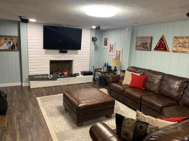 Spacious living area featuring a white painted brick fireplace surround, wood-finish flooring, light blue paneled walls, and recessed lighting