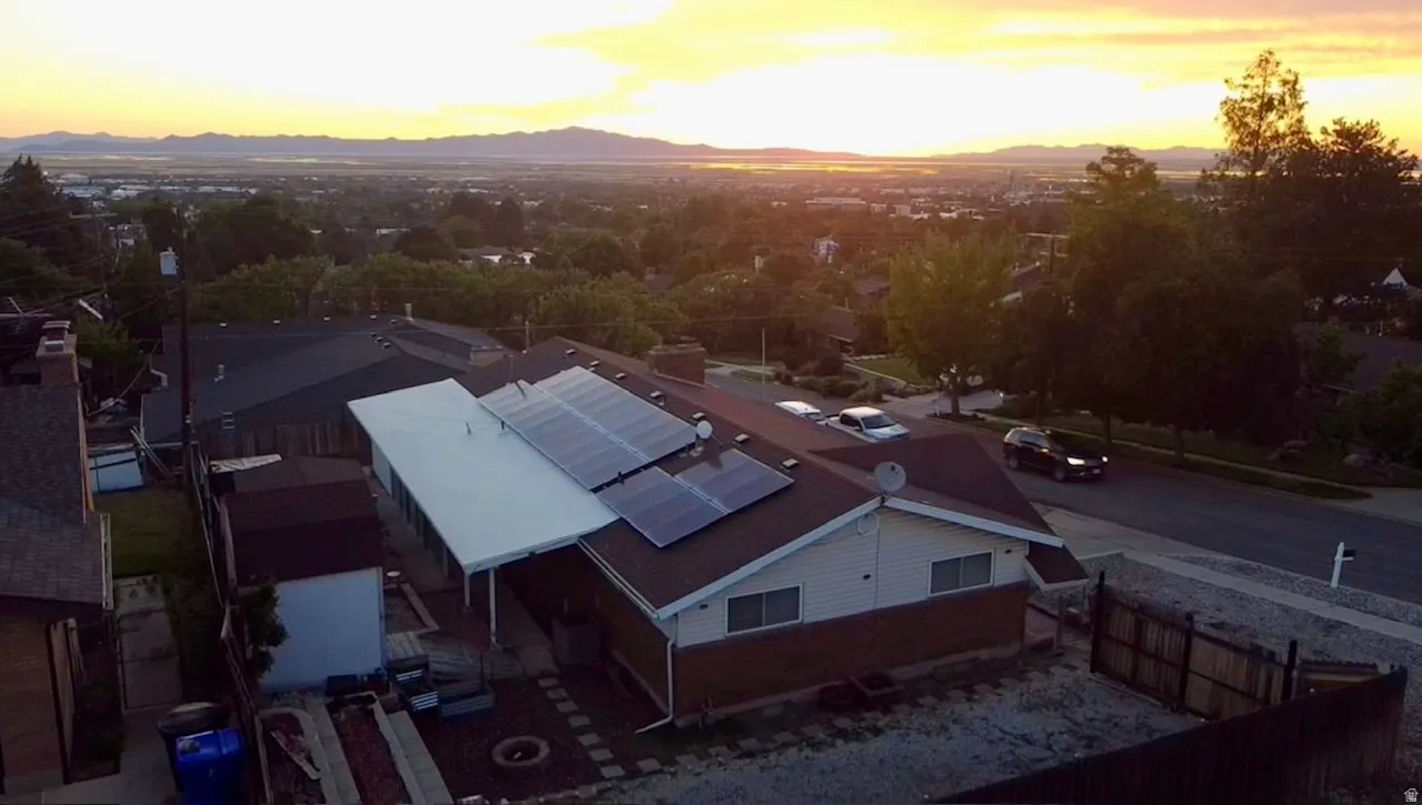 Residential property featuring multiple roof-mounted solar panels, a covered patio extension, and a terraced backyard area