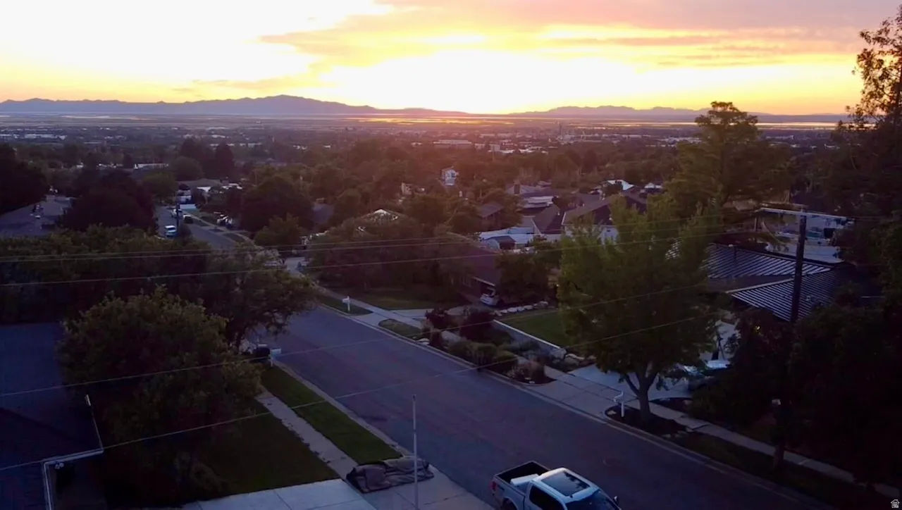 Expansive aerial perspective showcasing a residential neighborhood with distant mountains and a body of water under a twilight sky