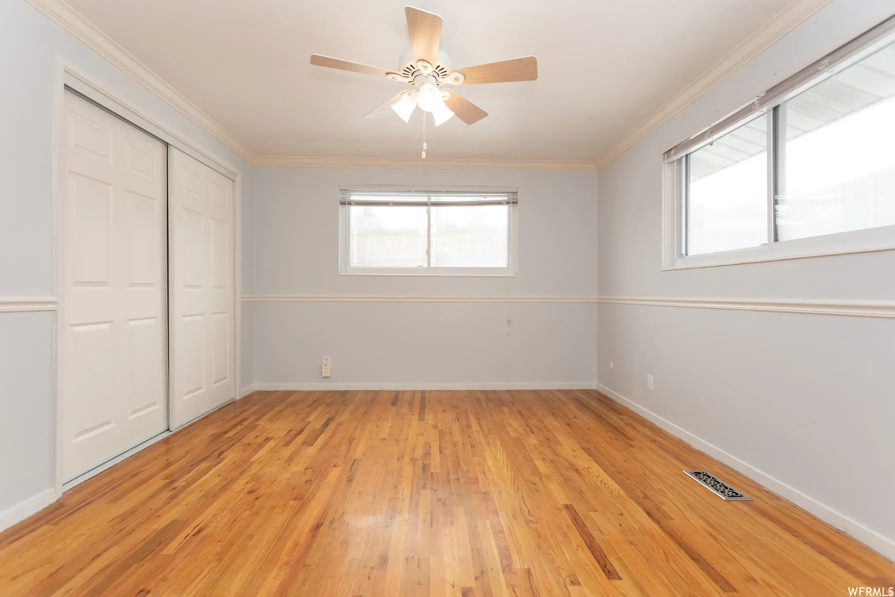 Primary Bedroom. Hardwood flooring extending throughout, complemented by a ceiling fan with integrated lighting
