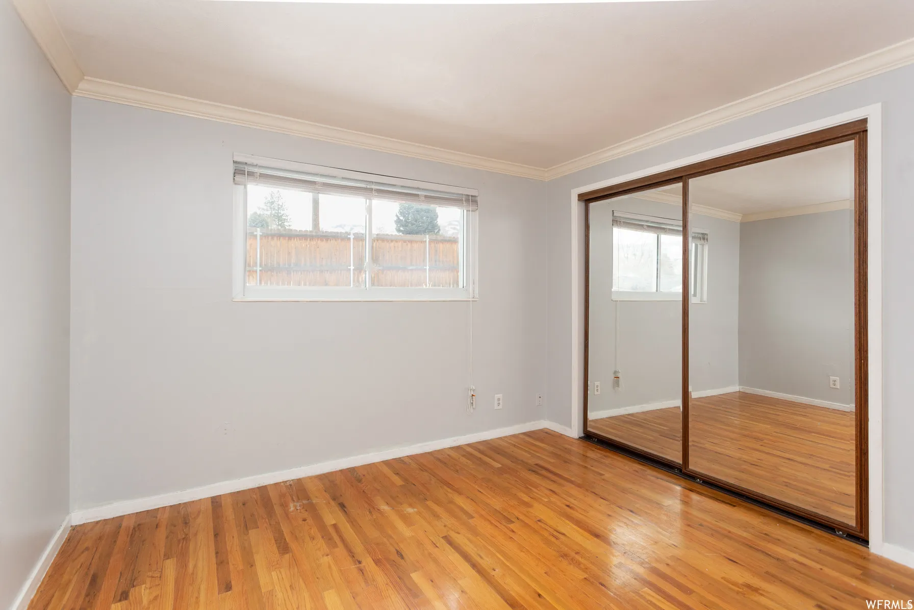Room featuring wood-finish flooring, light grey painted walls, and white crown molding