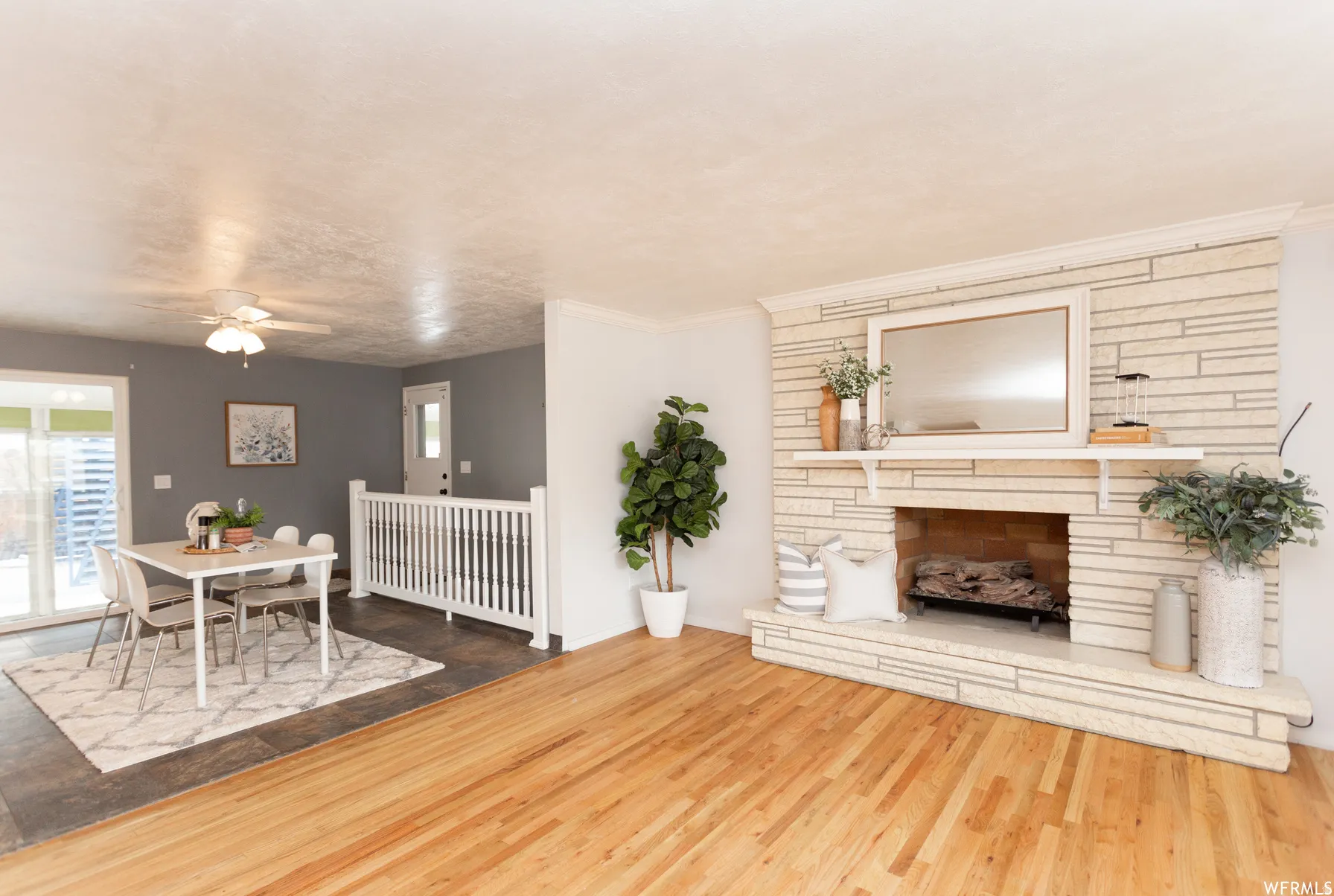 Spacious living area featuring wood-finish flooring and a stone-clad fireplace with a mantel shelf