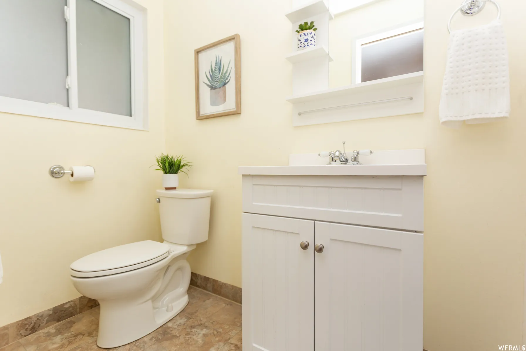 en suite bathroom. White vanity with brushed nickel hardware, a single basin sink, and a chrome faucet