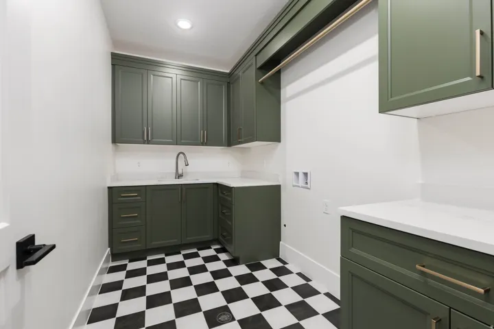 Custom cabinetry with gold-tone hardware, white countertops, built-in sink with faucet, recessed lighting, and checkered tile flooring