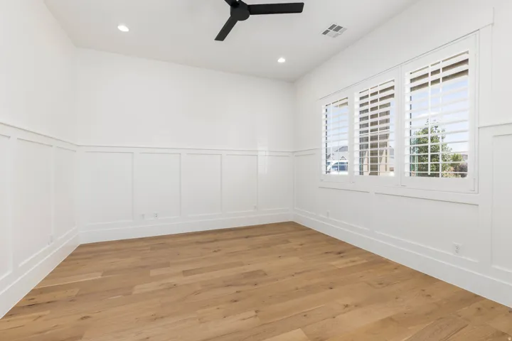 High vaulted ceiling, recessed lighting, wood-finish flooring, white plantation shutters, and decorative wainscoting
