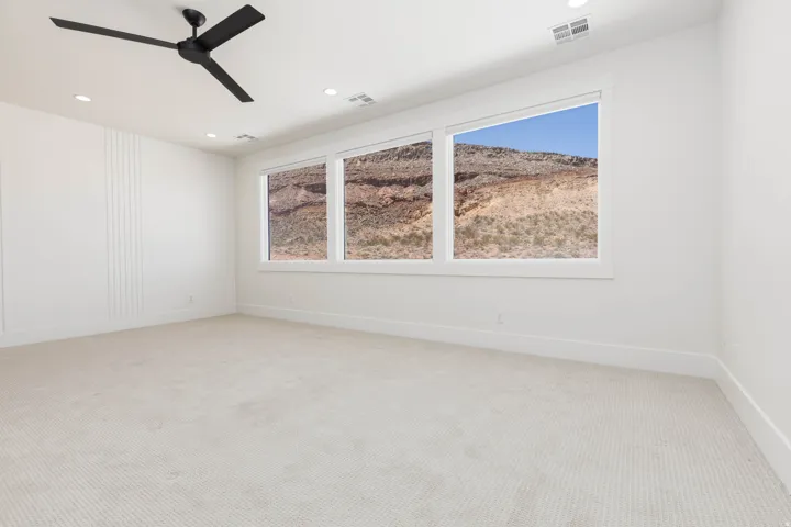 Expansive room with neutral carpeting, recessed lighting, and a modern ceiling fan