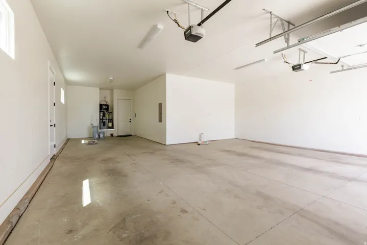 Spacious garage with multiple overhead garage door openers, concrete flooring, and built-in overhead lighting
