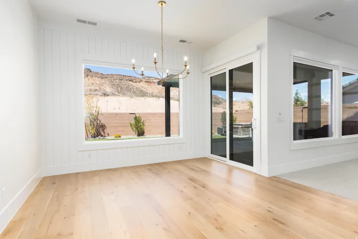 Light wood-finish flooring, white shiplap accent wall, large picture window, glass sliding door, and a chandelier