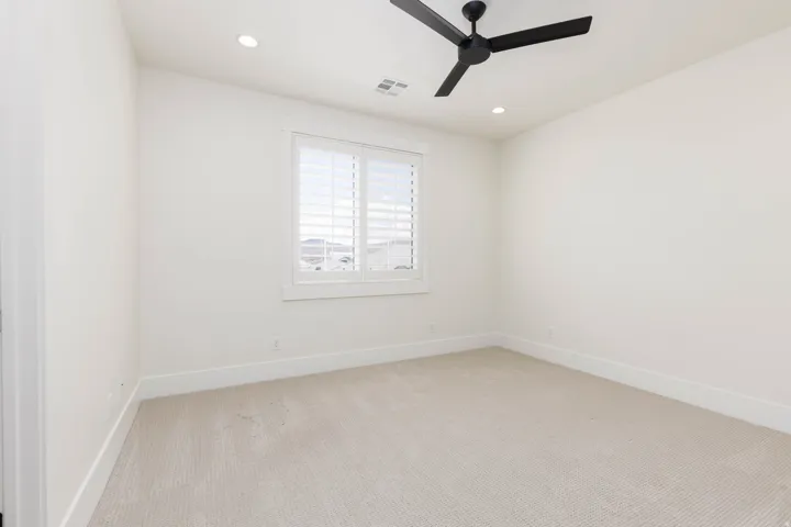 Recessed lighting, ceiling fan with black blades, window with plantation shutters, light-toned carpeting, and white trim