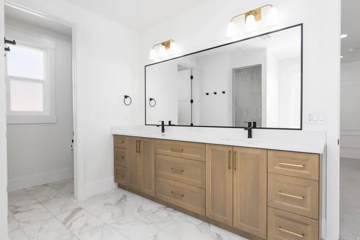 Dual vanity with light wood-finish cabinetry, white stone countertops, and matte black plumbing fixtures