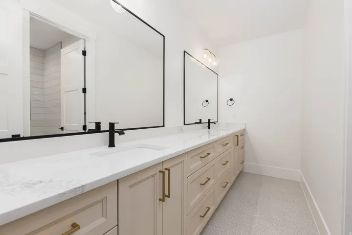Dual vanity featuring light-toned cabinetry, white countertops, matte black faucets, and rectangular mirrors