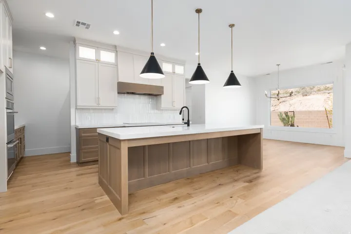 Chef's kitchen featuring a spacious island, built-in double ovens, white shaker cabinetry, and wood-finish flooring