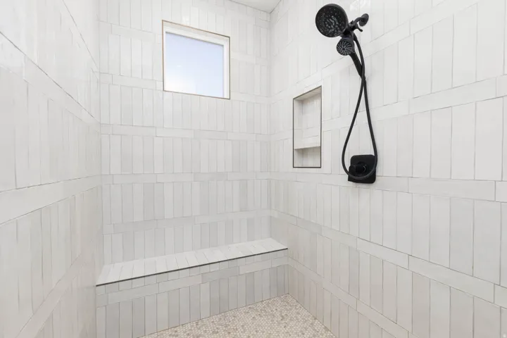 Tiled shower with a built-in bench, recessed niche, and a fixed window