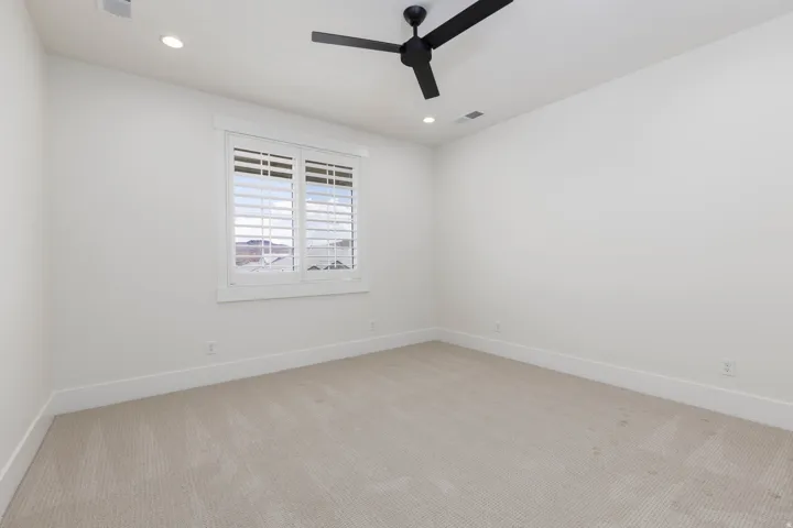 Recessed ceiling lighting, white plantation shutters, and a black ceiling fan