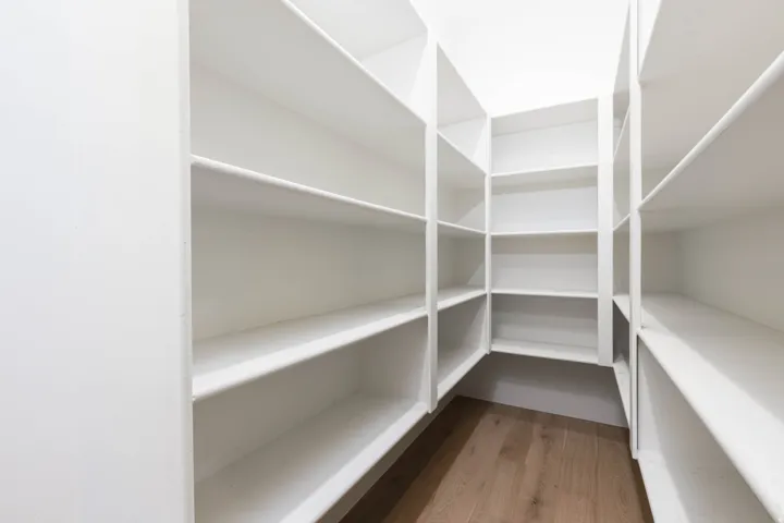 Walk-in pantry featuring extensive white shelving and wood-finish flooring