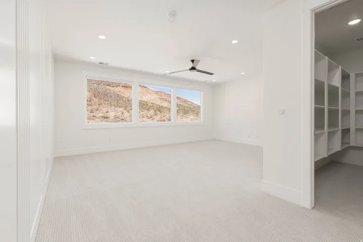 Spacious room featuring broad windows with mountain scenery, a ceiling fan, recessed lighting, and light-toned carpeting