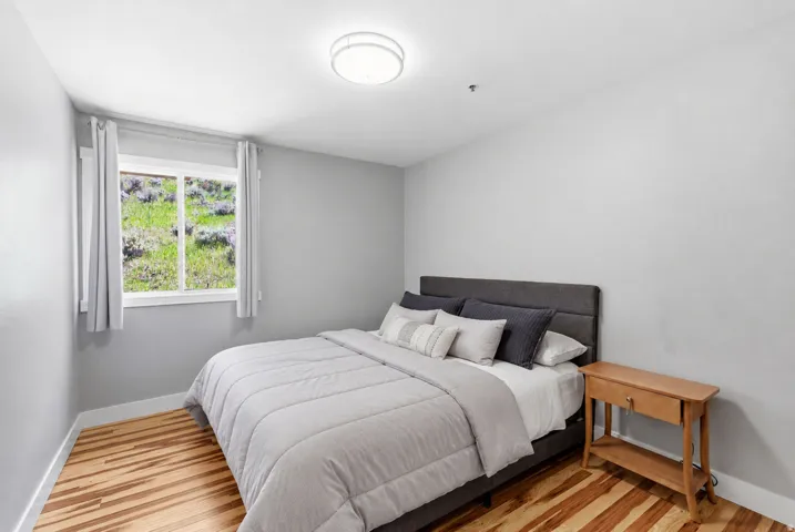Bright interior space featuring wood-finish flooring, a single window with white trim, and a flush-mount ceiling light fixture