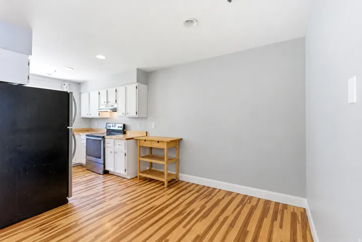 Kitchen featuring wood-finish flooring, white cabinetry, light countertops, and stainless steel appliances