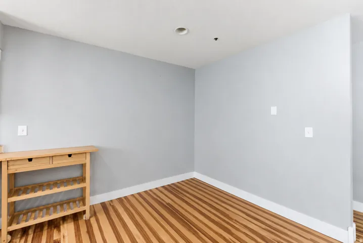 Room featuring light gray painted walls, white trim, wood-finish flooring, and a recessed ceiling light
