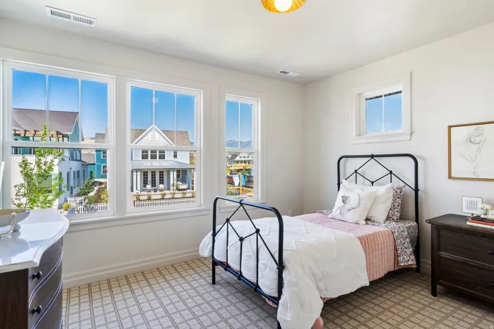 Bright room featuring multiple windows, patterned carpet flooring, a ceiling-mounted light fixture, and white painted walls