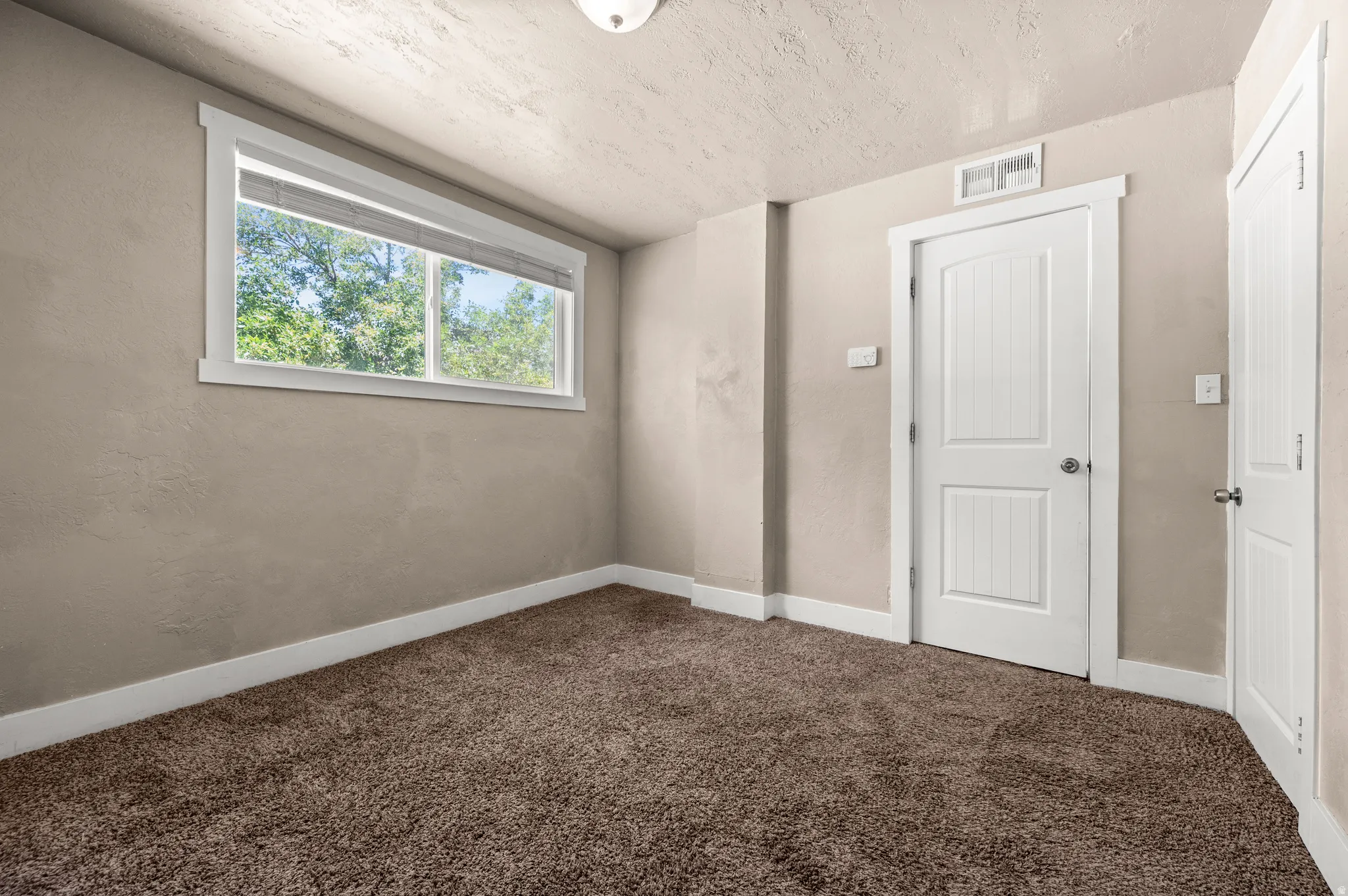 Neutral tone walls featuring white baseboards, a white-framed window, and two white panel doors
