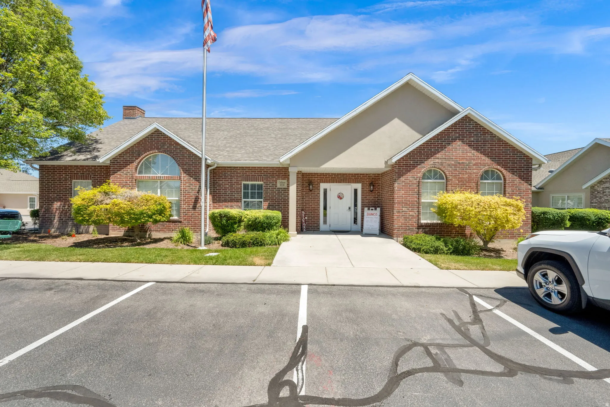 Brick facade building featuring arched and rectangular windows, a central white entry door, and light-colored siding accents