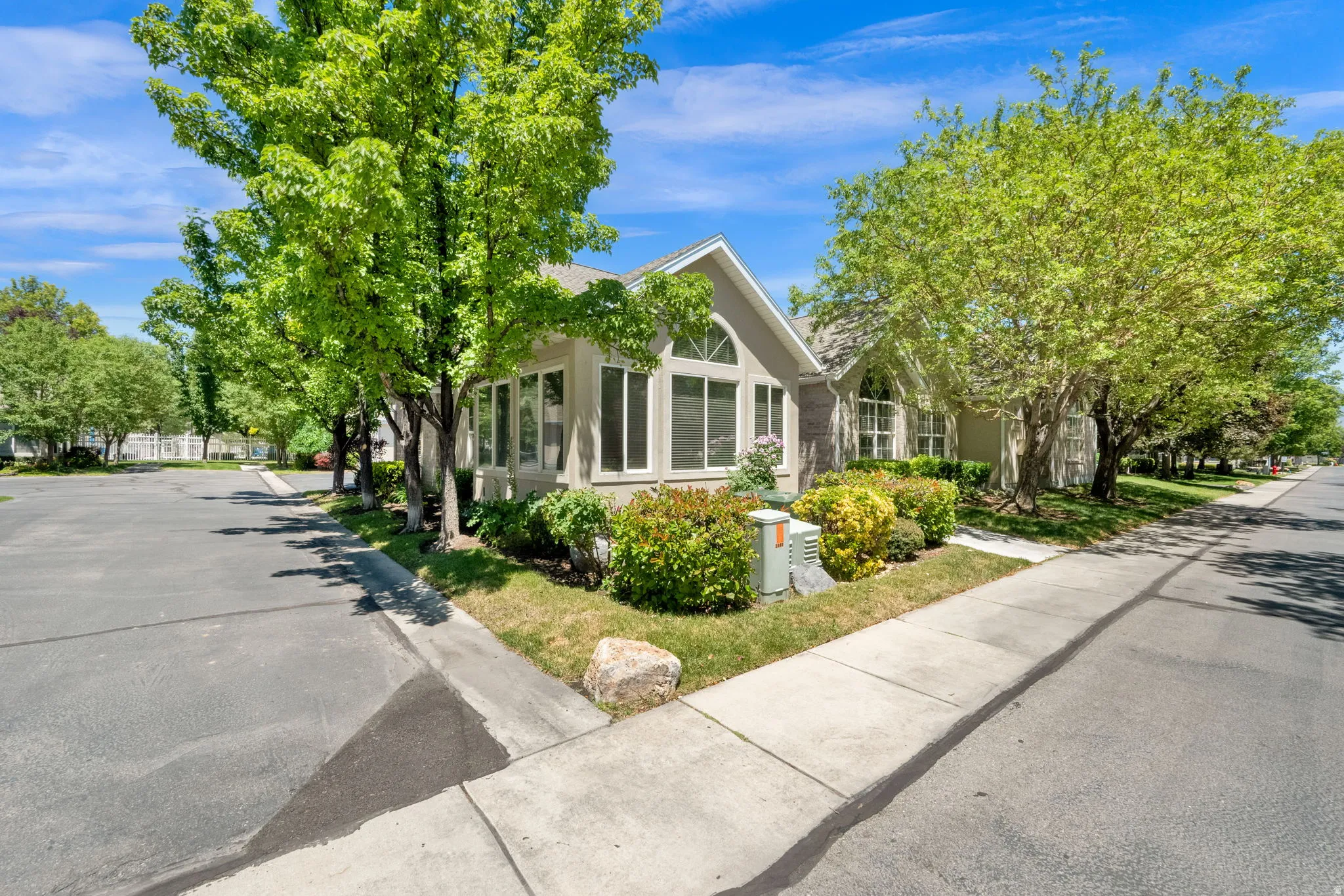 Exterior property featuring multiple large windows, mature trees, and established landscaping
